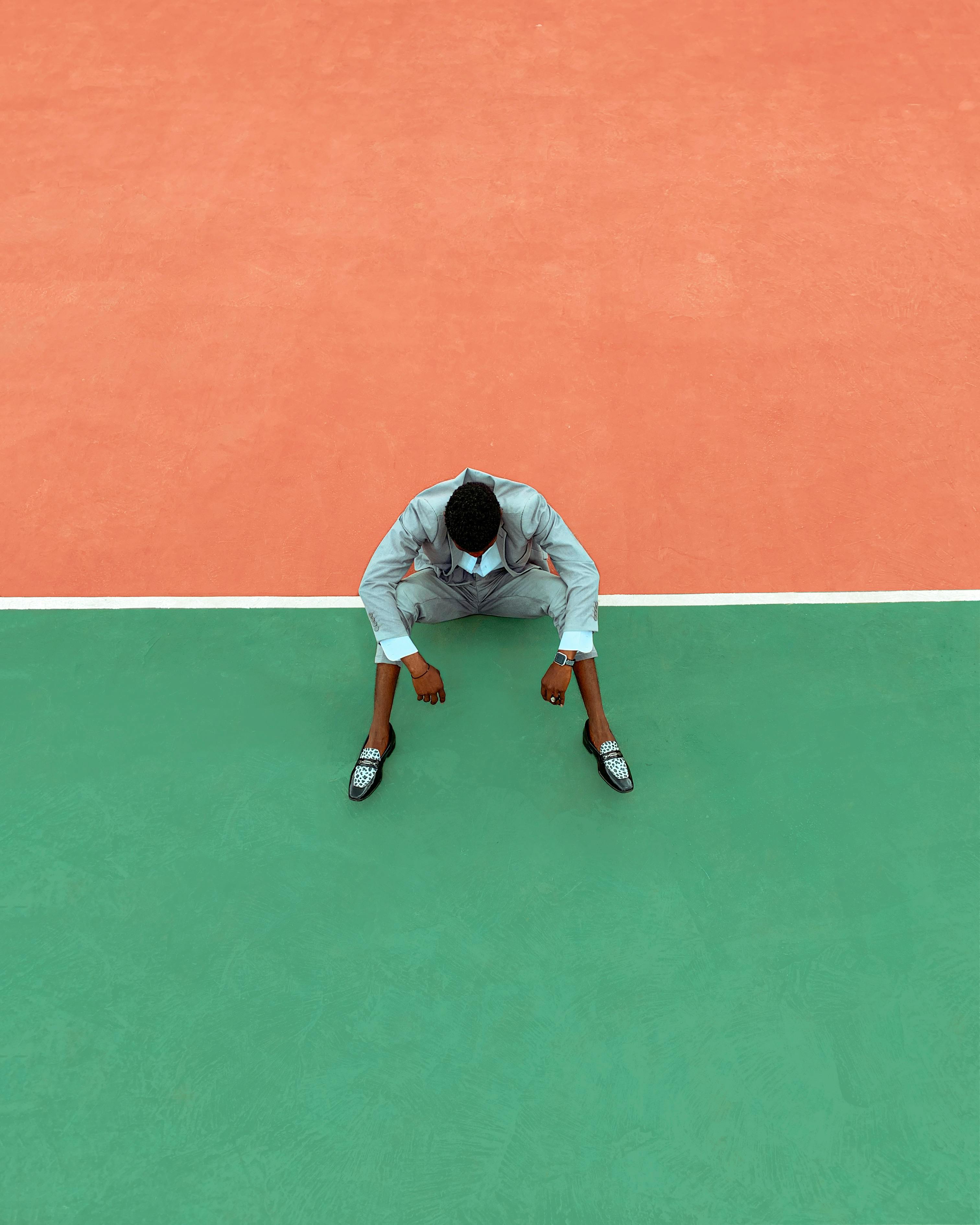 Aerial photo of a man in a suit on a colorful court, contrasting orange and green surfaces.