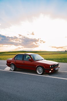 A stunning vintage red car parked on a scenic countryside road during sunset, evoking a classic vibe.
