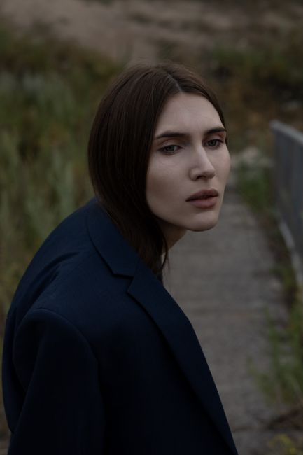 Elegant portrait of a brunette woman in dark jacket taken outdoors in Astana.