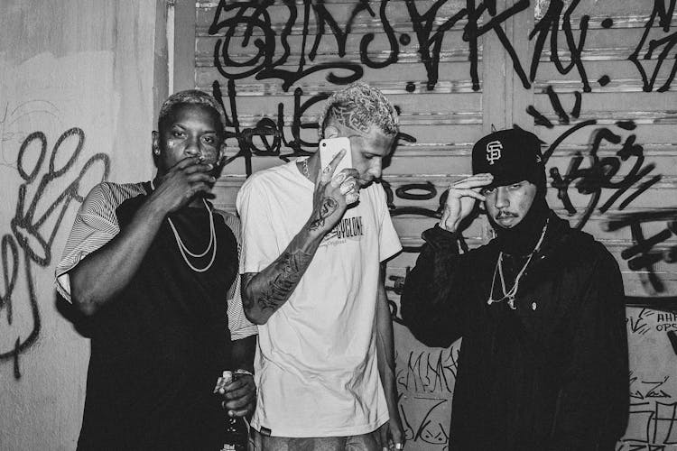 Hip Hop Men Posing Against Graffiti On Wall