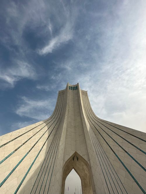 Free Stunning upward shot of the iconic Azadi Tower in Tehran, Iran against a partly cloudy sky. Stock Photo