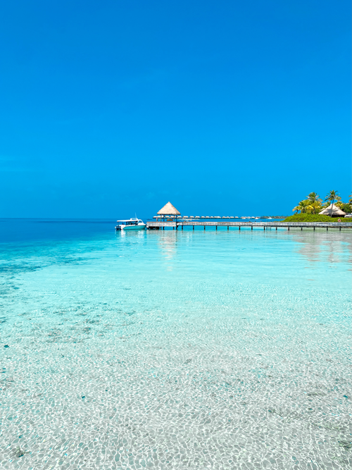Free Stunning view of a tropical pier extending into crystal clear ocean waters under a bright blue sky. Stock Photo