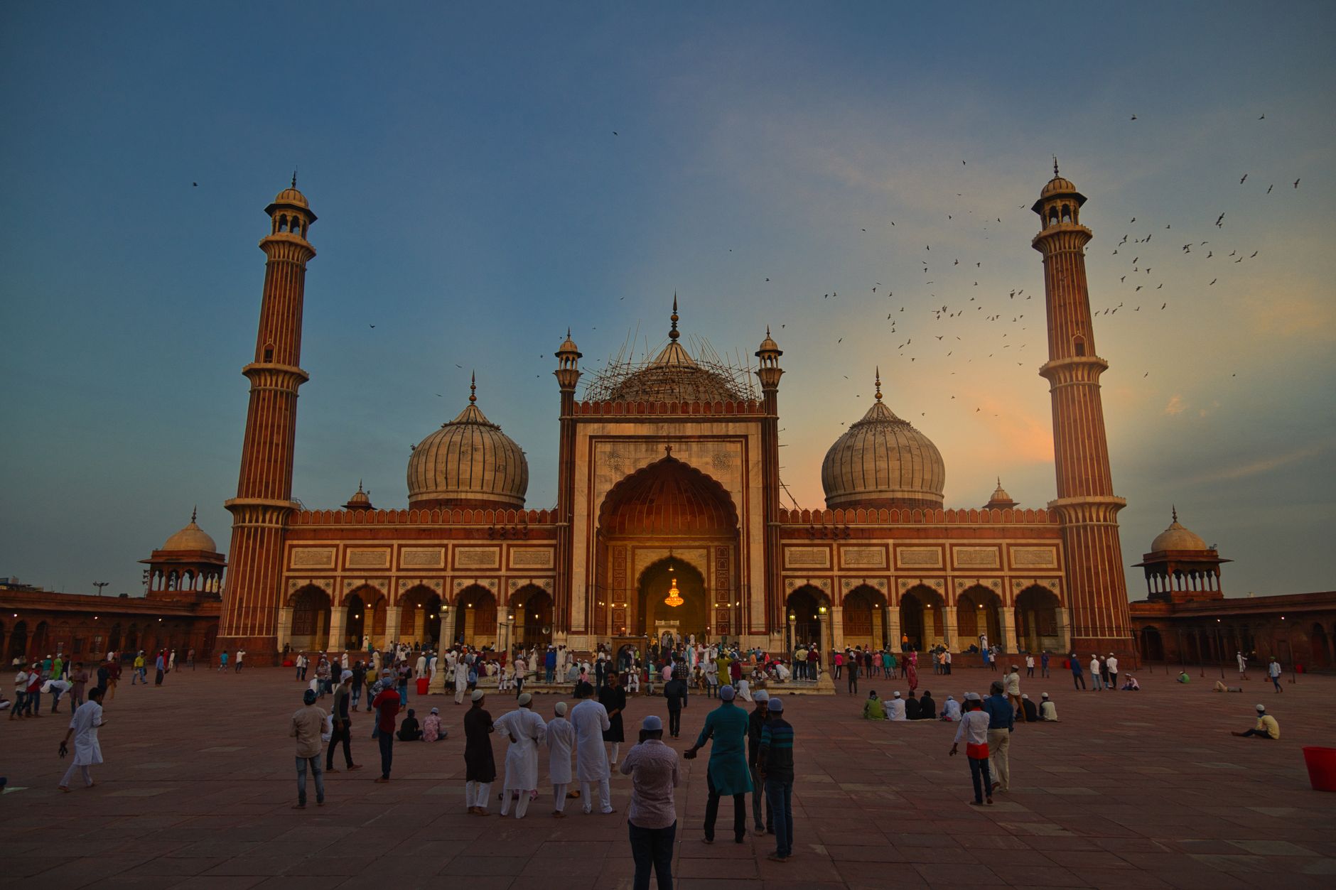 Crowded lane in Chandni Chowk with spice sacks, cycle rickshaws and the domes of Jama Masjid behind