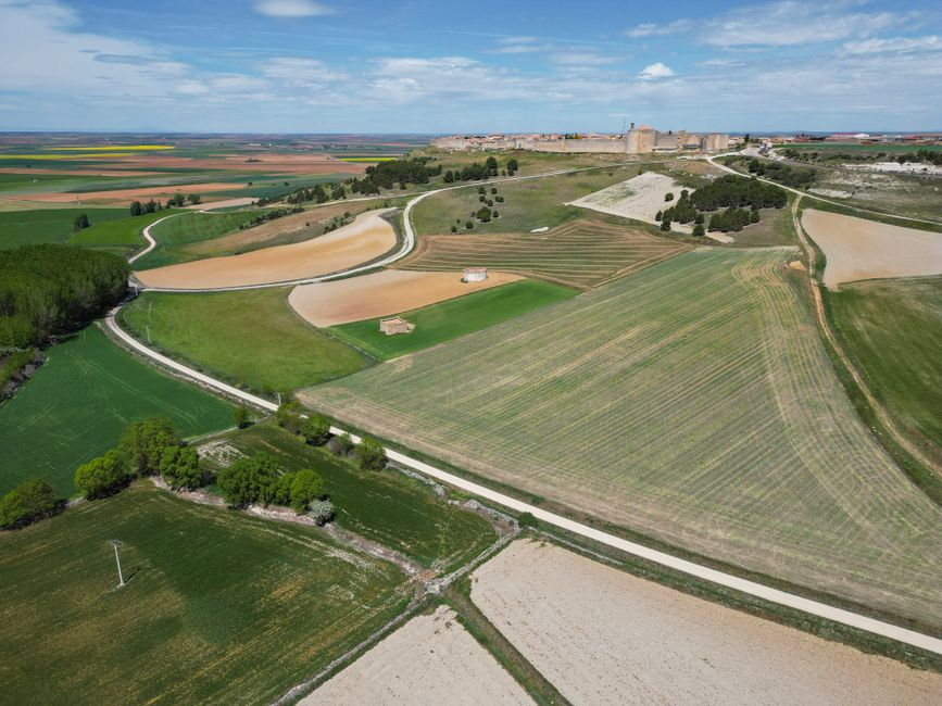 Vista aérea escénica de campos exuberantes y del pueblo histórico de Urueña, España, mostrando la belleza rural.