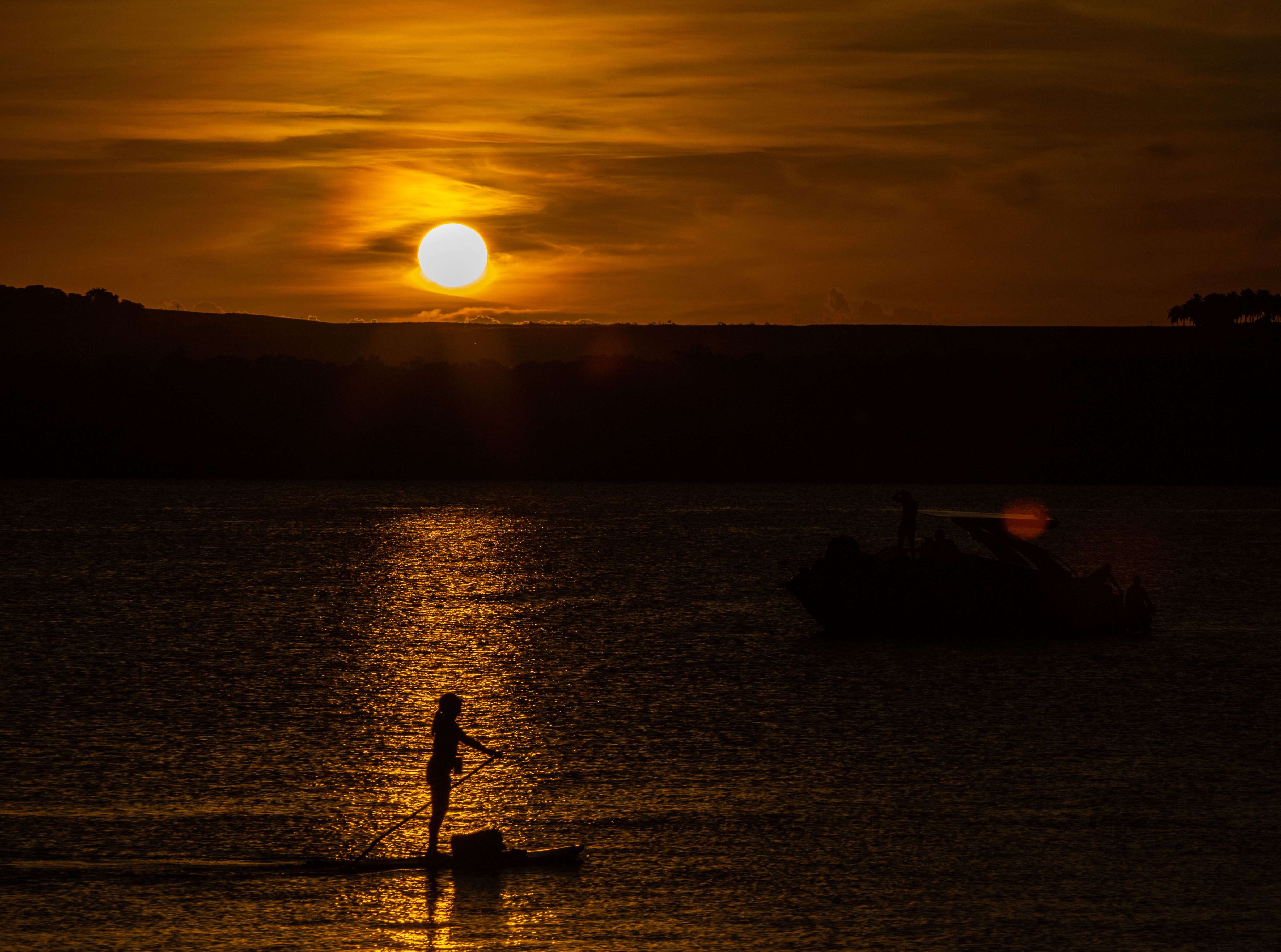 Silhouette of Person Standing on Canoe on Lake at Sunset · Free Stock Photo