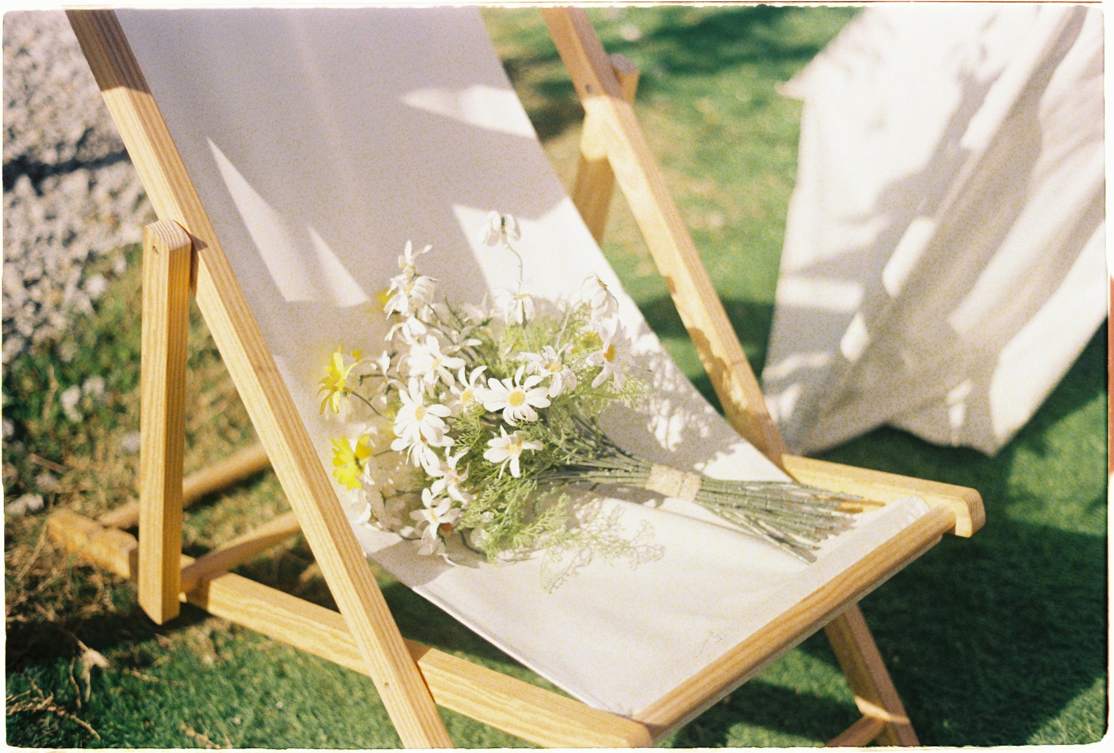 A calming outdoor setting featuring a bouquet of white daisies on a sunbed, basking in sunlight.