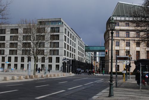 Free A dynamic street scene in Berlin, featuring modern architecture and bustling city life under a cloudy sky. Stock Photo