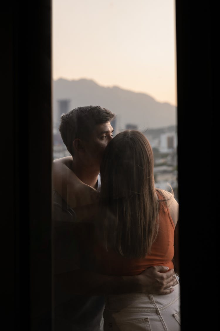 A Couple Kissing Through A Window At Sunset