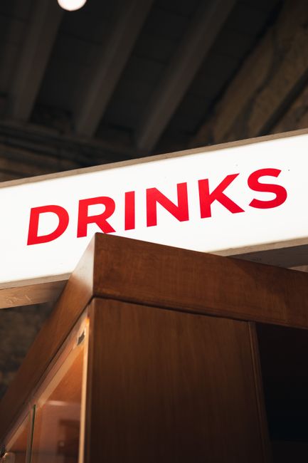 Close-up of a bright 'Drinks' sign in a warm, inviting pub interior, perfect for nightlife scenes.