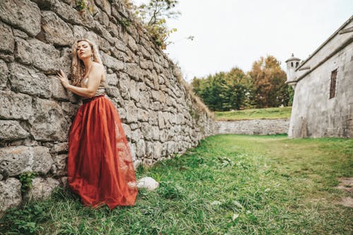 Woman in Evening Dress Leaning on Stony Wall