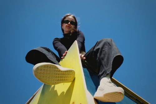 Free Low angle shot of a woman in sunglasses seated on a vibrant structure against blue sky. Stock Photo