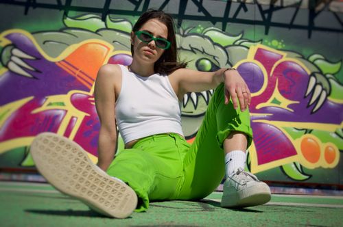 Free Street fashion photo featuring a woman in vibrant pants against a graffiti wall. Stock Photo