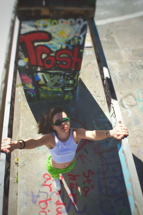 Free Young woman in sunglasses stands among vibrant graffiti art, viewed from above. Stock Photo