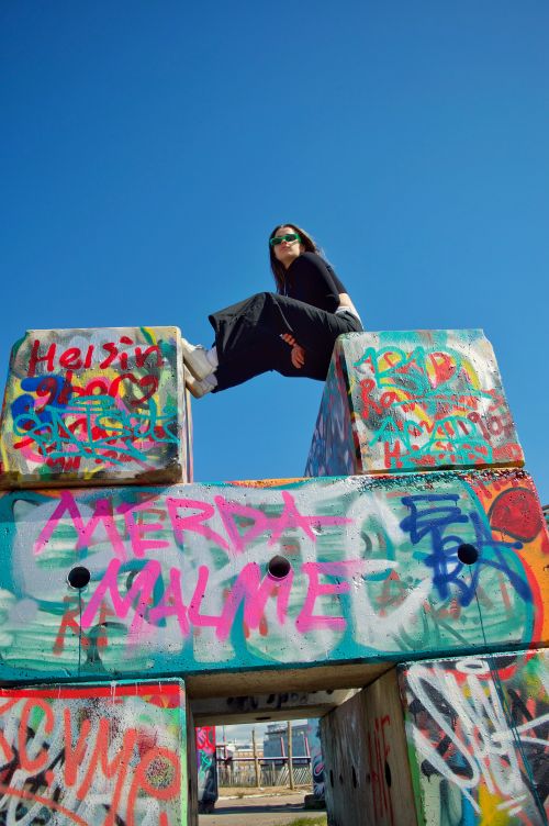 Free Woman posing on vibrant graffiti blocks, embracing urban culture. Stock Photo