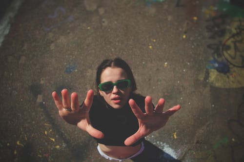 Woman in Sunglasses Posing with Hands Raised