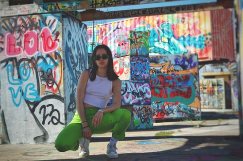 Free Stylish woman posing in vibrant urban graffiti setting, showcasing street fashion. Stock Photo