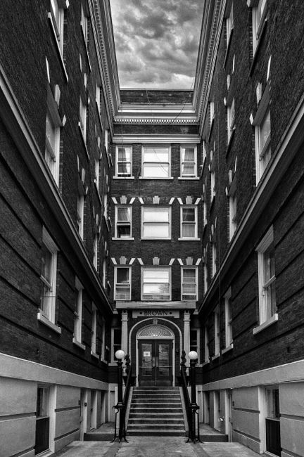 Dramatic black and white photo of an urban alley with classic architecture.