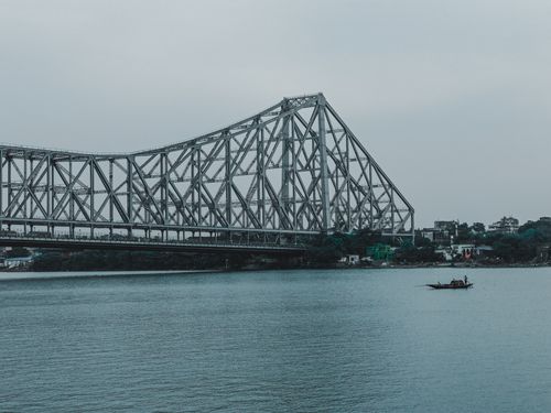 Free Stunning view of Howrah Bridge spanning the Hooghly River in Kolkata, with a boat floating below. Stock Photo
