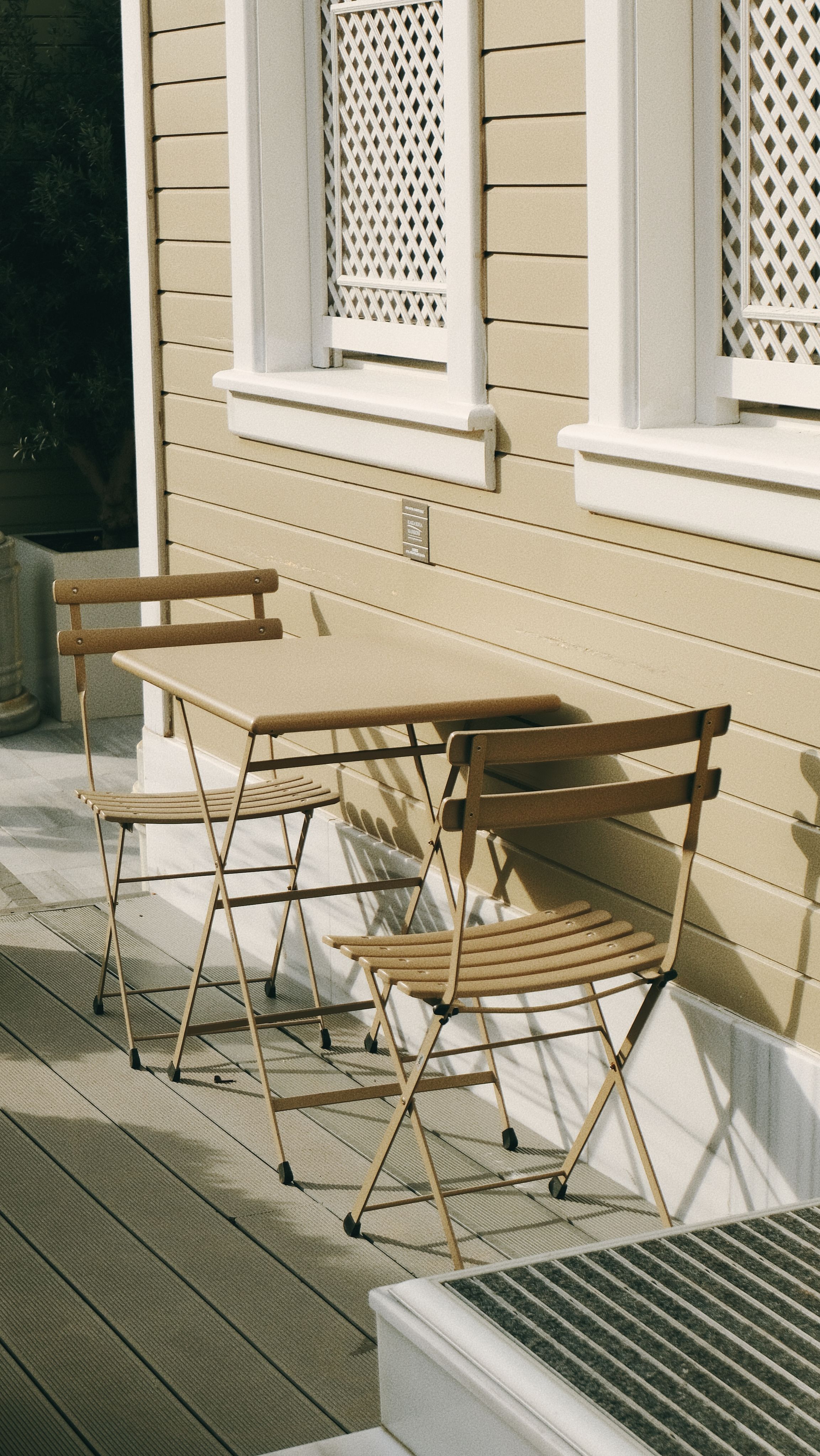 Side patio design with gray composite decking flooring, with a small bistro set placed on the surface