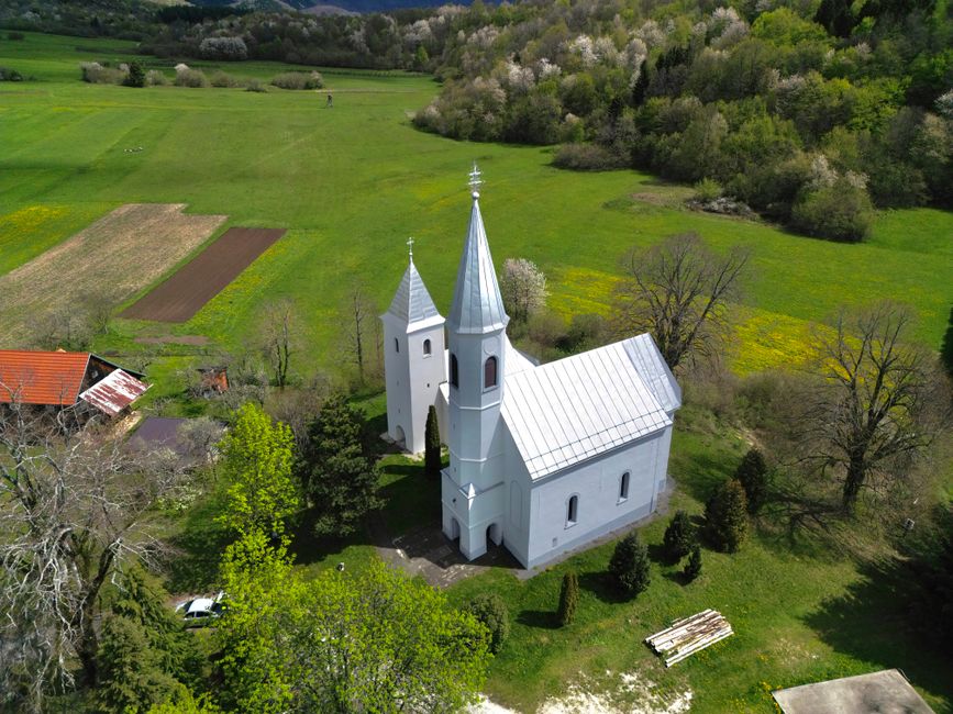 Aerial view of a historic white church in the rural countryside of Sošice, Croatia.