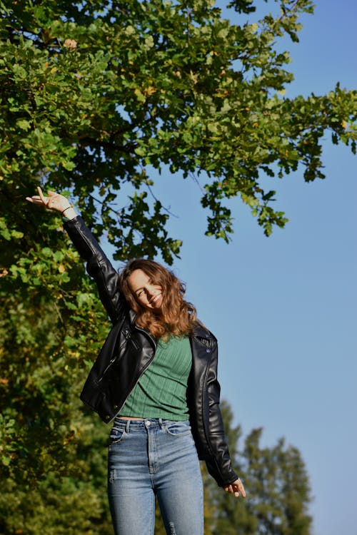 Smiling Woman in Leather Jacket Standing with Arm Raised
