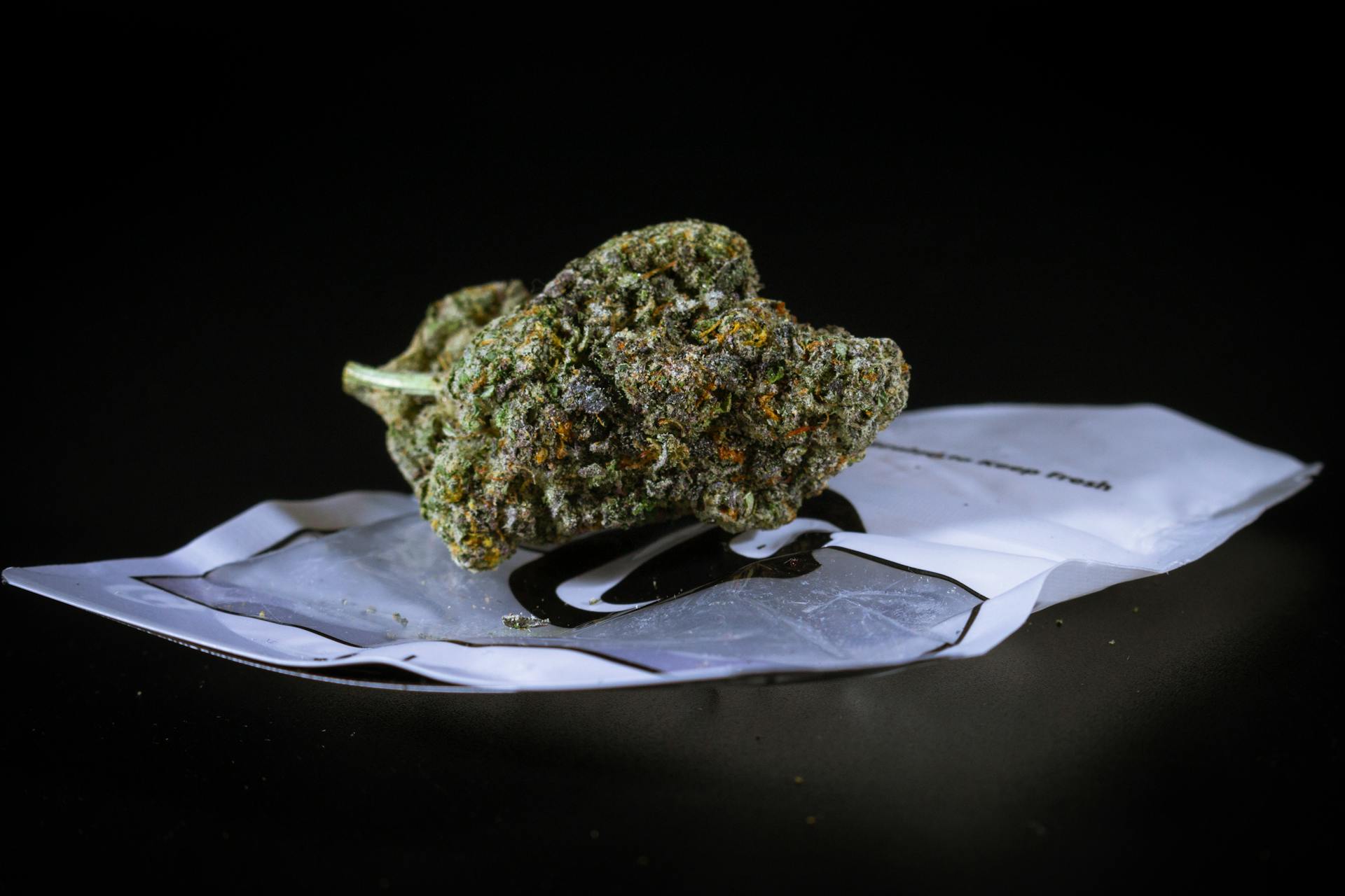 Detailed image of a cannabis bud with trichomes on a black background. High-quality macro shot.