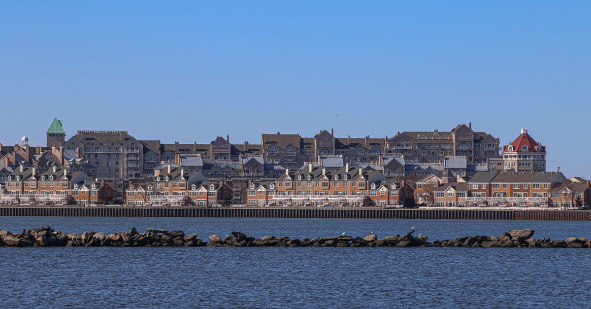 Panoramic view of Jersey City skyline from waterfront, showcasing urban architecture and serene waters.