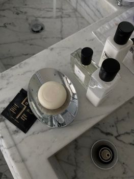 Marble bathroom countertop featuring soap, lotion, and skincare products arranged aesthetically.