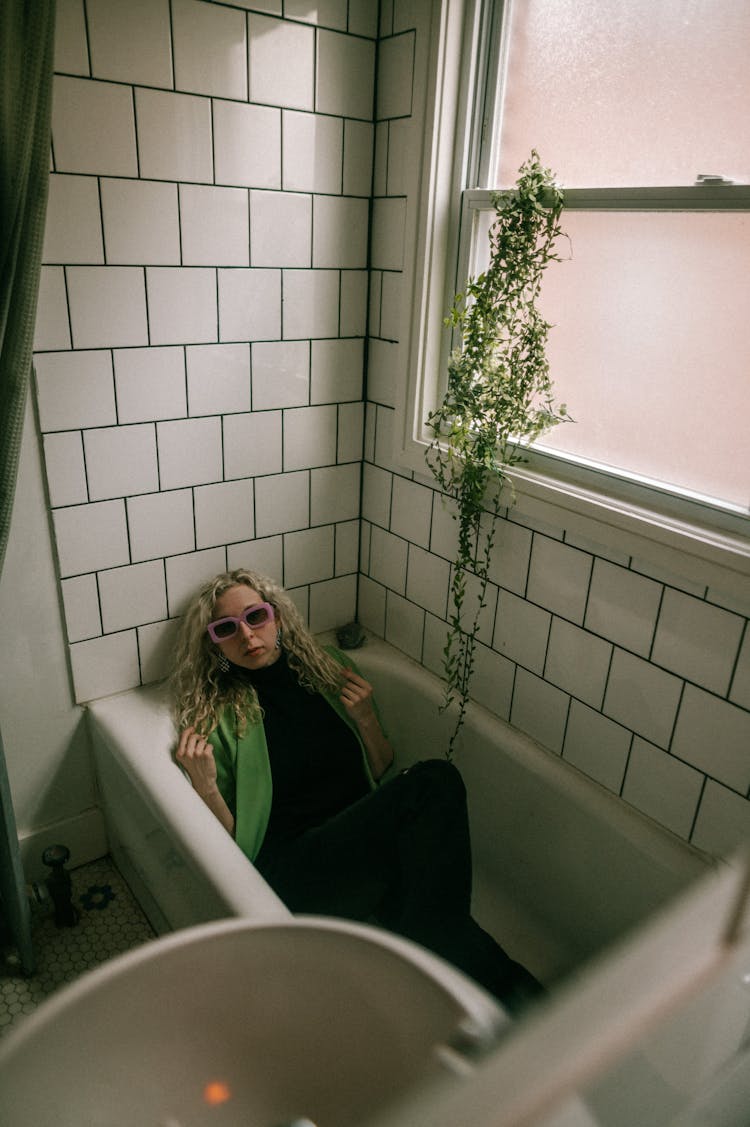 Woman In Green Jacket Sitting In Bathtub