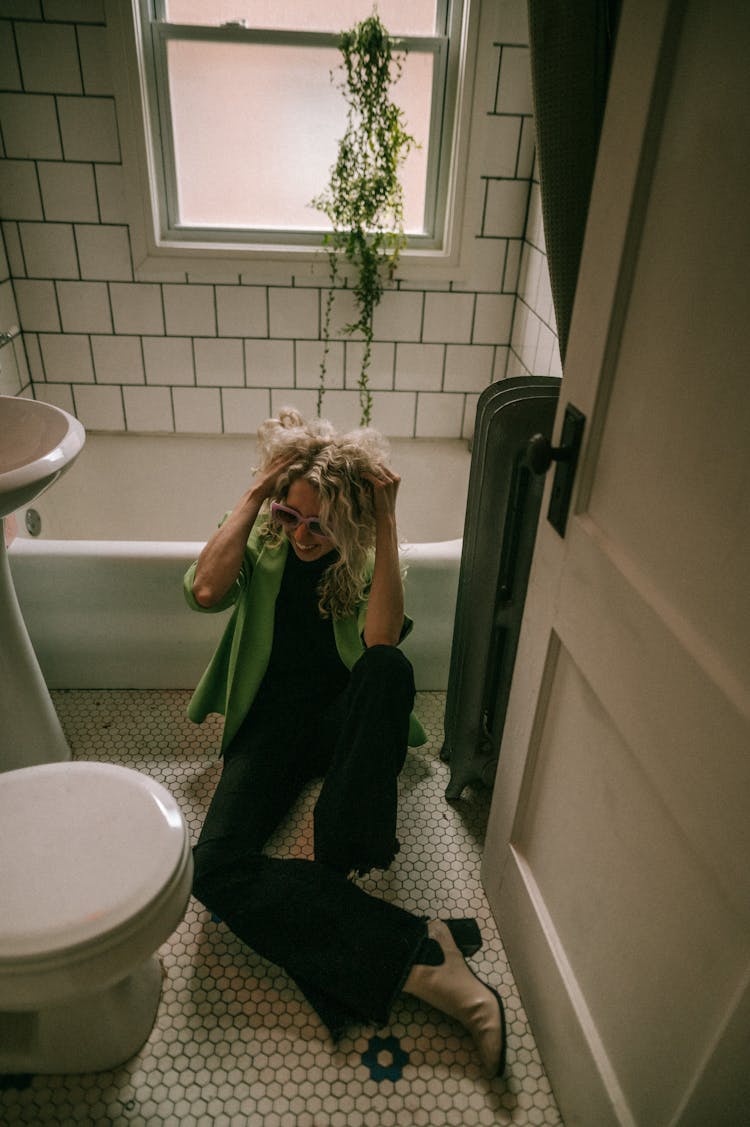 Laughing Woman Sitting On Floor In Bathroom