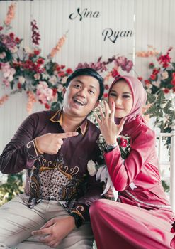 A couple celebrating their engagement with joyful expressions and floral decorations. - Fotografer Sidoarjo