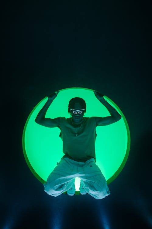 Person with Sunglasses Posing Against Green Light