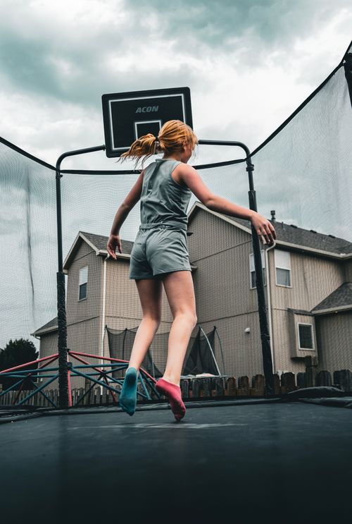 Free A teenager enjoys a fun jump on a trampoline in a residential backyard setting. Stock Photo