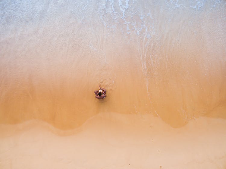 Aerial Photography Of Man Sitting On Beach