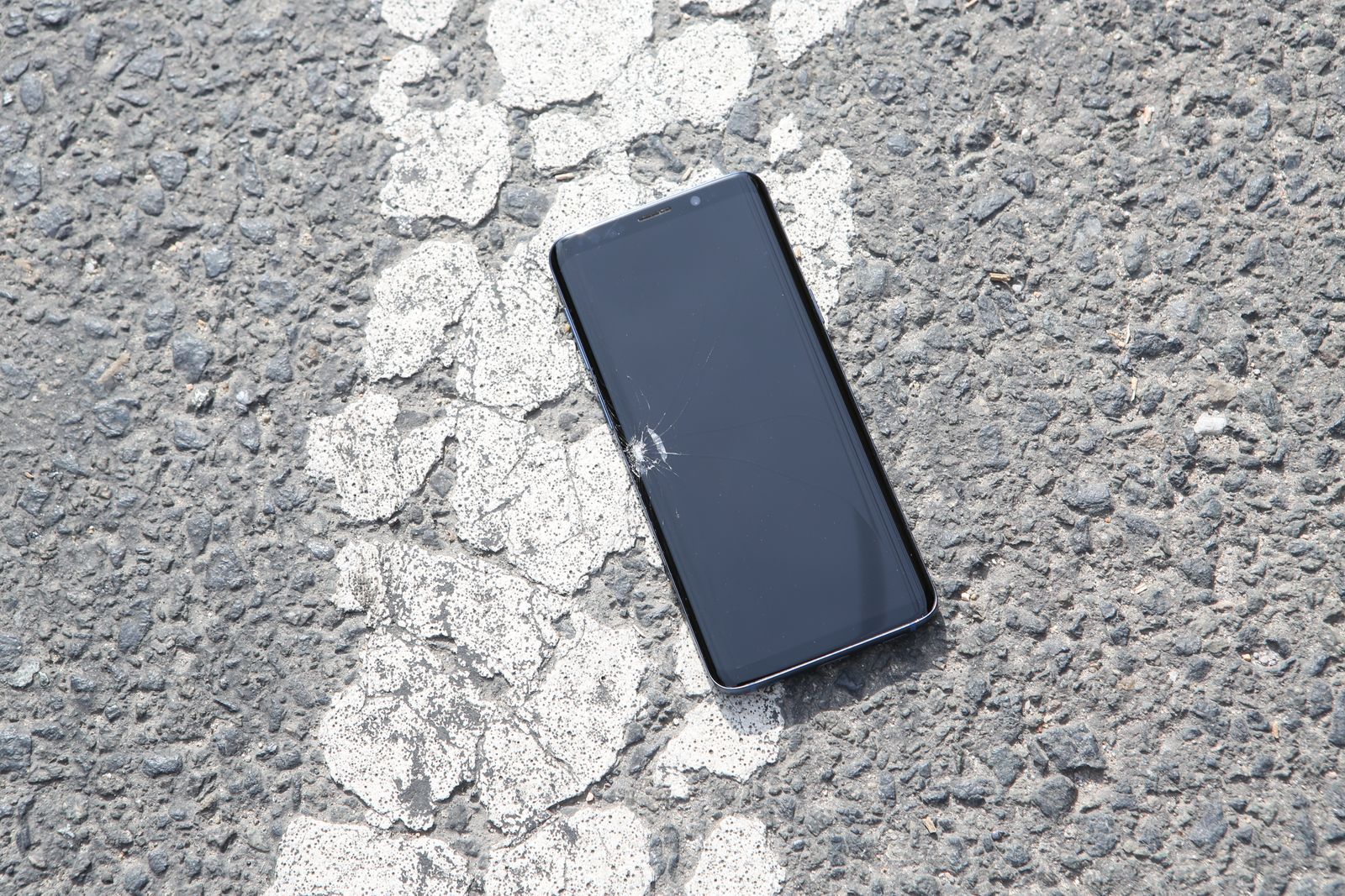 Cracked smartphone lying on asphalt after a drop