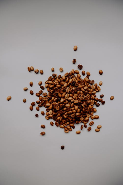 Scattered Coffee Beans on White Surface 