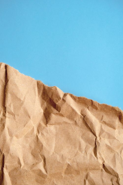 Free A crumpled brown paper on a vibrant blue background, providing textured contrast. Stock Photo
