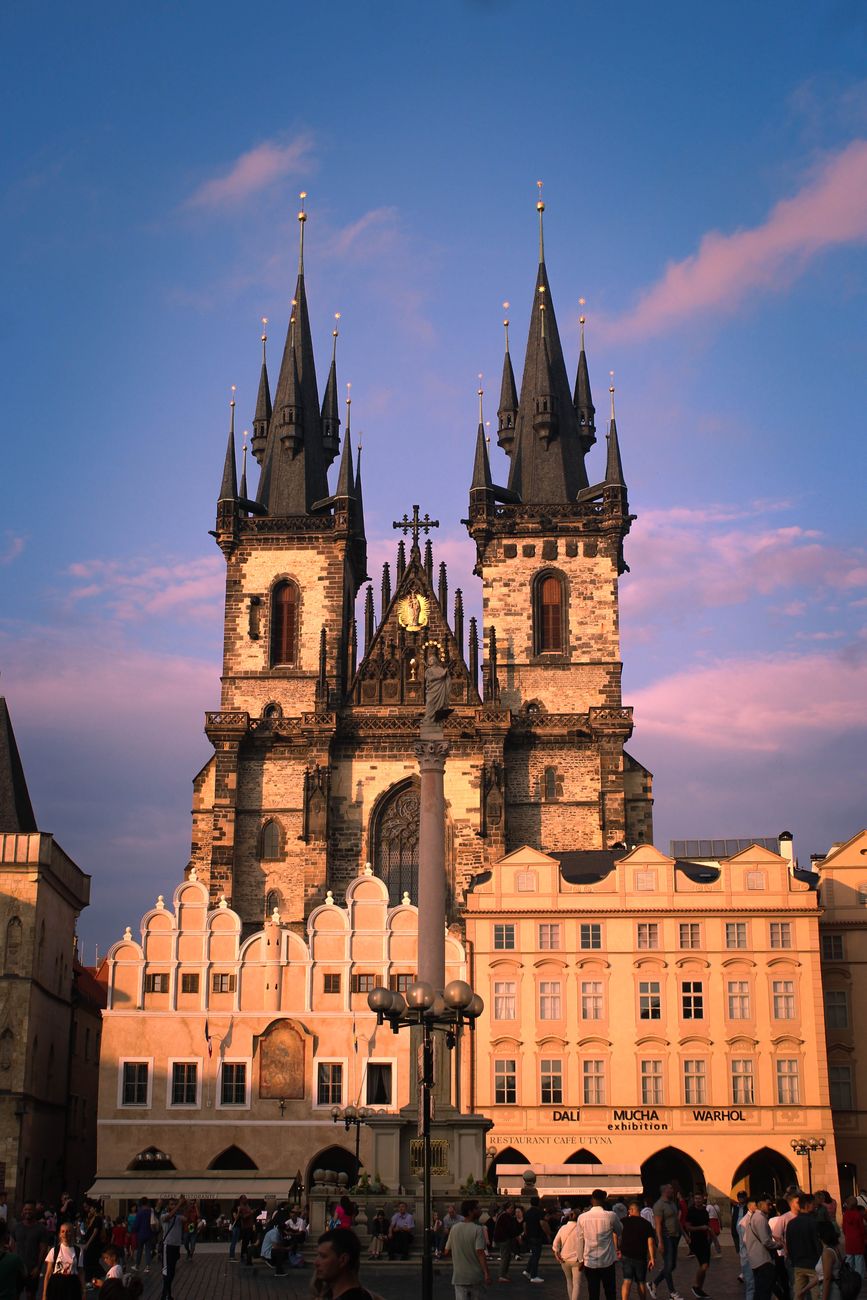 Gothic twin-spired church illuminated at dusk in a historic old town square — the church architecture and civic heritage that anchors colonial districts.
