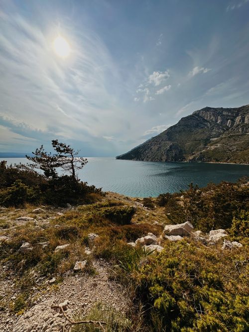 Free Scenic view of a sunlit coastal cliff with a calm sea under a vibrant summer sky. Stock Photo