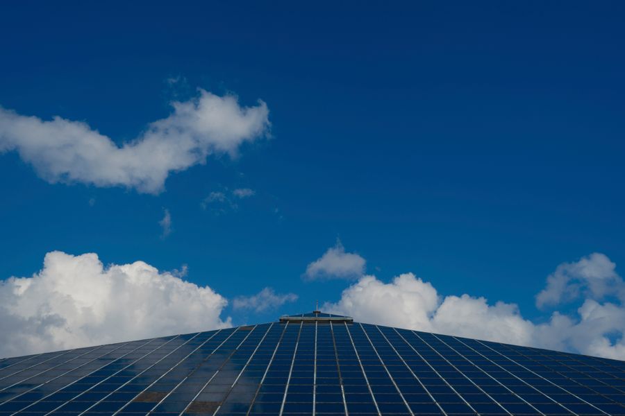 Solar panels reflecting a clear blue sky with scattered clouds, symbolizing renewable energy.