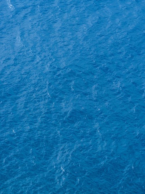 Free Tranquil aerial view of a clear blue ocean with gentle waves creating a peaceful and relaxing atmosphere. Stock Photo