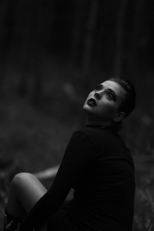 A woman in black and white sitting in the woods