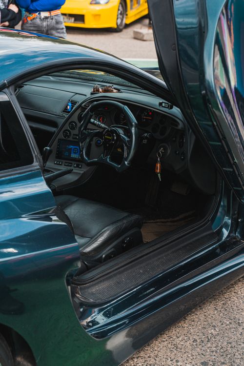 Free Close-up view of a sports car interior with open door, featuring steering wheel and dashboard elements. Stock Photo