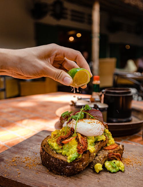 Close-up of Person Squeezing Lime Juice on an Avocado Toast 