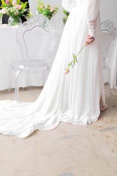 A bride in a flowing white wedding dress holding a pink rose, symbolizing romance and elegance.