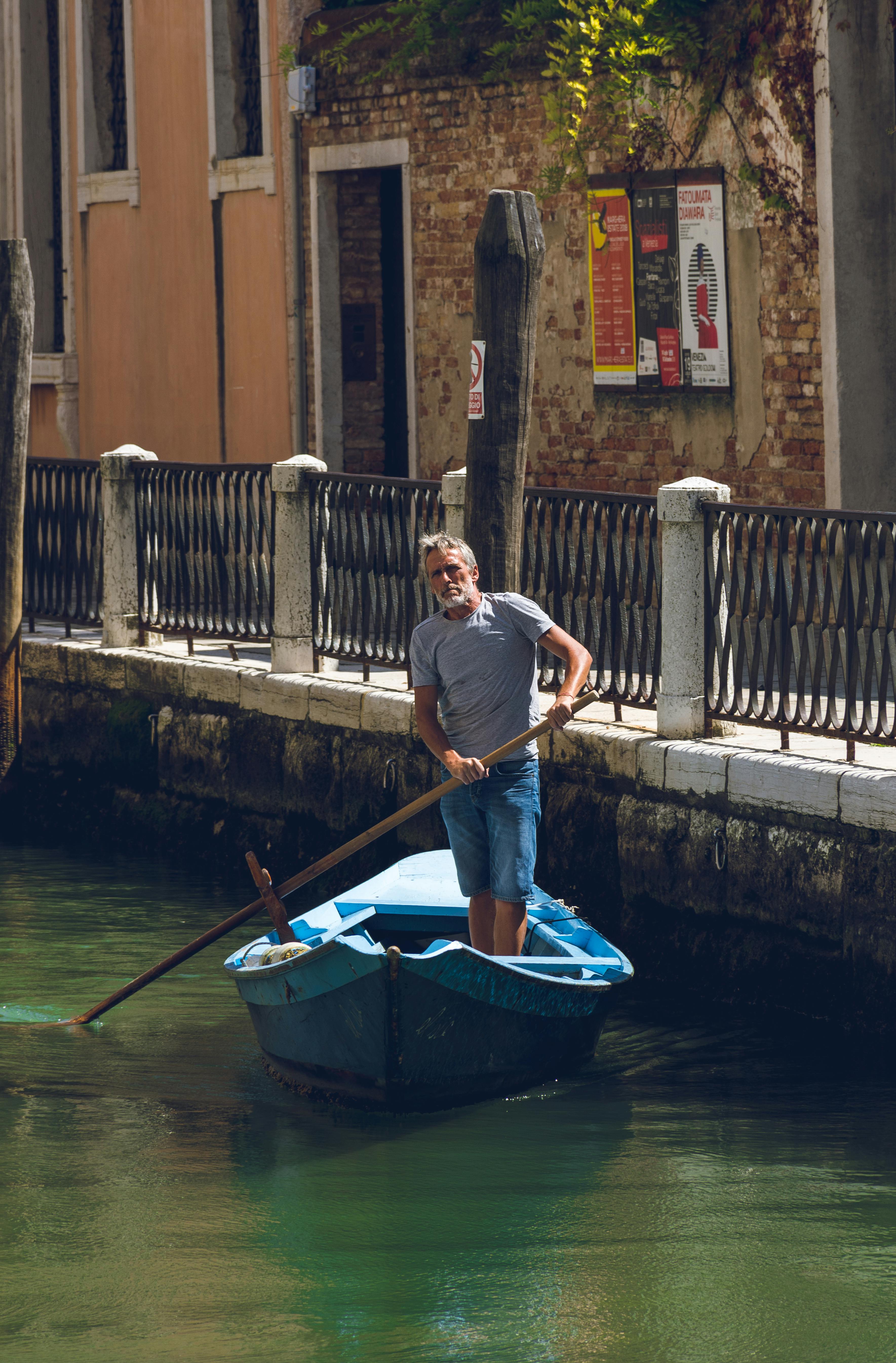 man riding a blue row boat