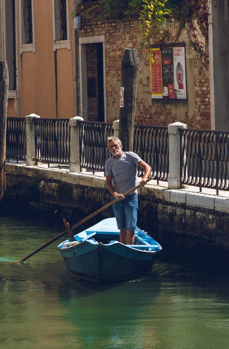 Man Riding A Blue Row Boat