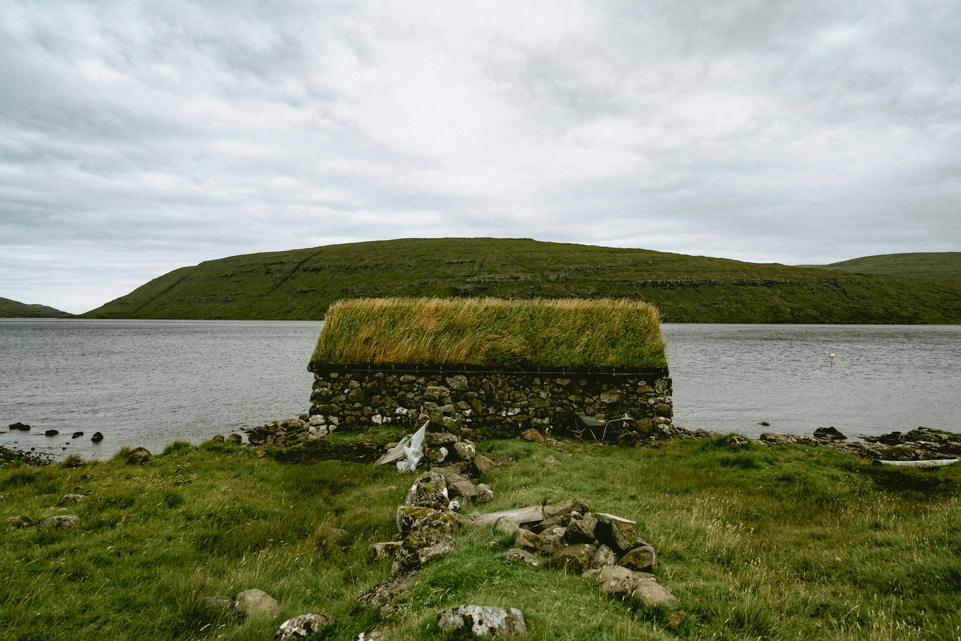 Stone Building with Grass on Roof near Water