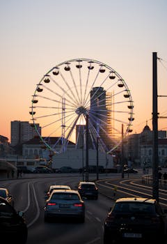A vibrant sunset scene of a Ferris wheel in Potsdam with cars and urban buildings.