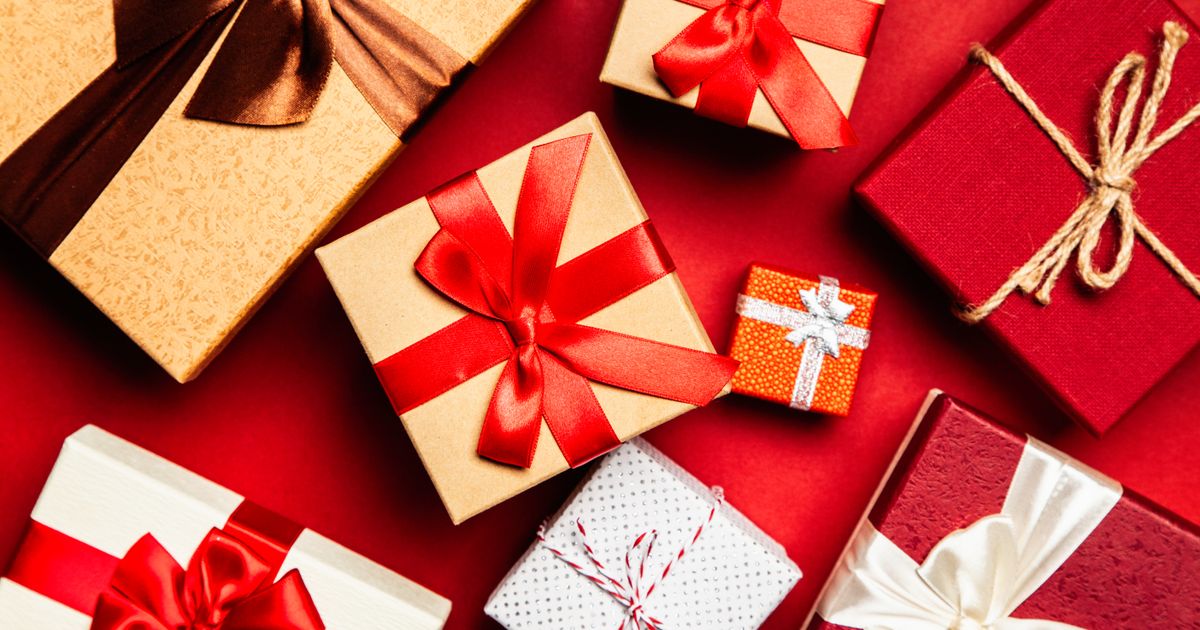 Colorful wrapped gift boxes with ribbons arranged on a red background